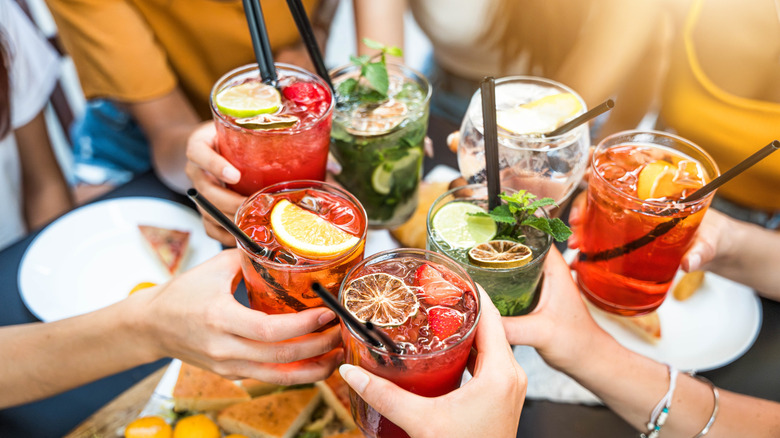 Group of people making a toast with colorful beverages