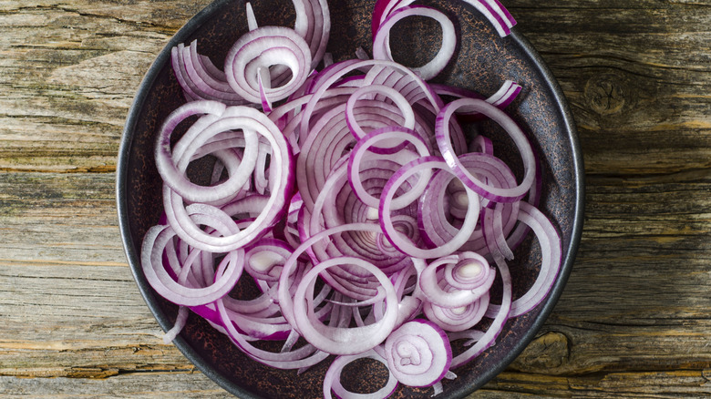 Bowl of sliced red onions on a wooden table