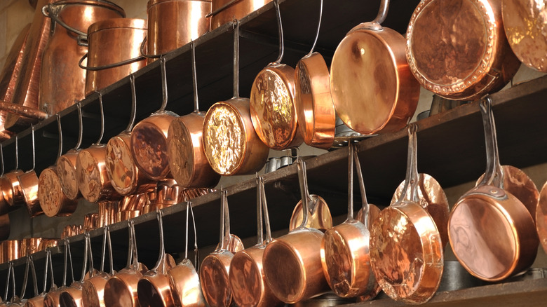 Shiny copper pans hanging from shelves