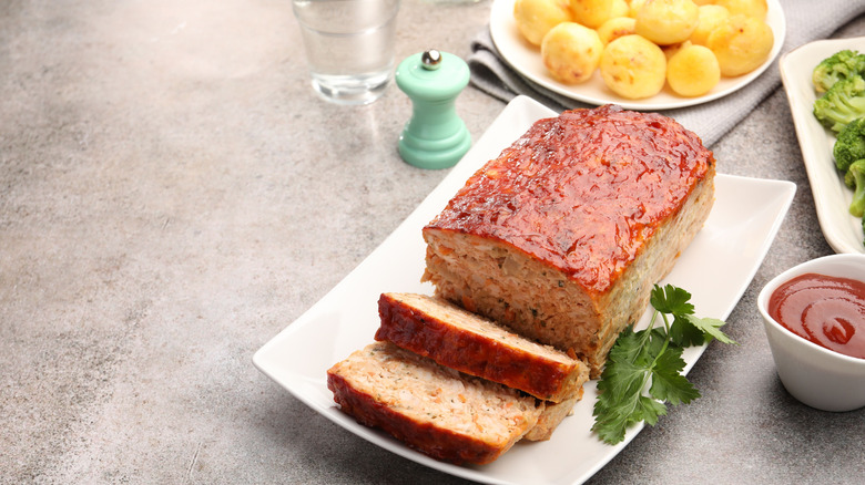 Meatloaf on a white plate with parsley and vegetables