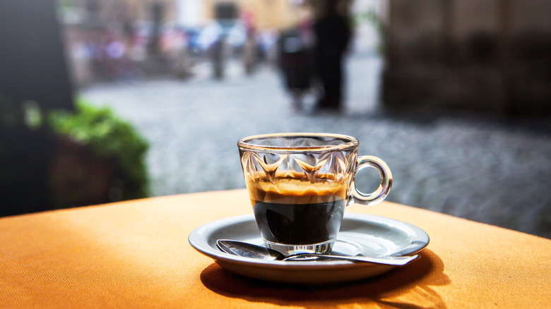 A glass of espresso sits on a table.