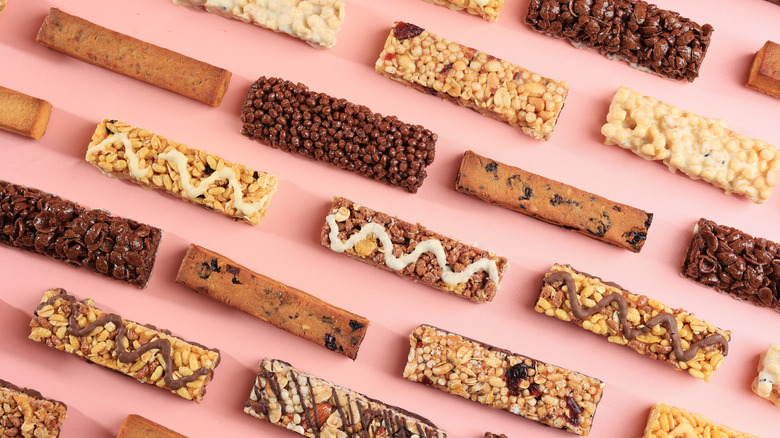 Various granola and protein bars on a pink background