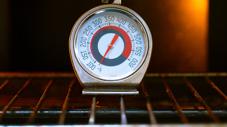An analog oven thermometer sitting on an oven rack