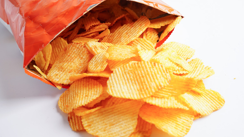 An open bag of potato chips with chips spilling out.