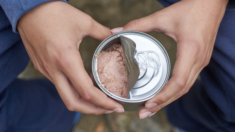 Person holding a half-open can of tuna