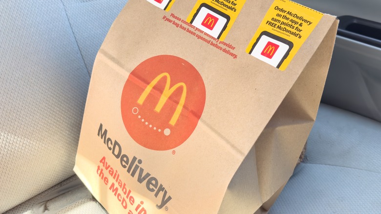 McDonald's bag featuring a McDelivery logo on a car seat