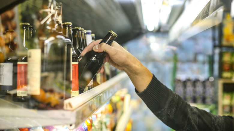 Hand picking beer out of fridge