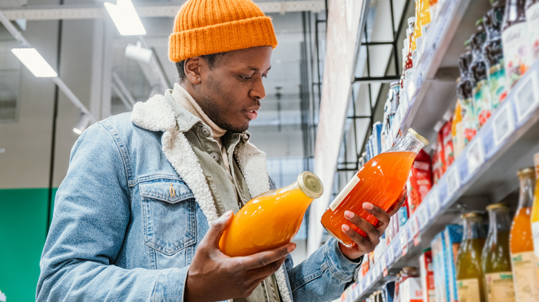 person looking at two different fruit drinks at store