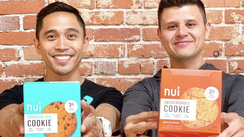 Nui founders Kristopher Quiaoit and Victor Macias holding two flavors of Nui cookies
