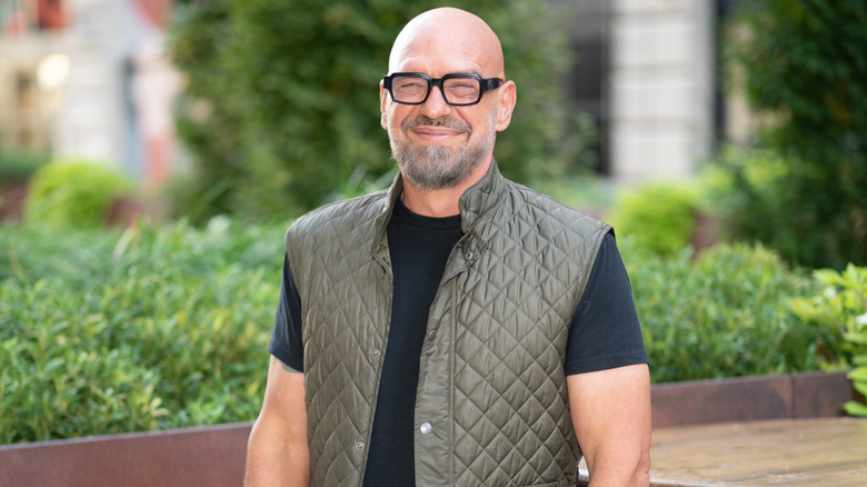 Chef Michael Symon standing on a patio surrounded by greenery