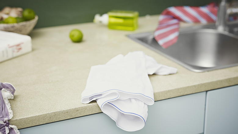 a white kitchen towel sits on a messy countertop