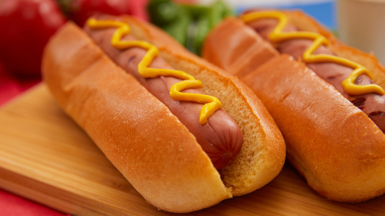 Two hot dogs in buns with mustard