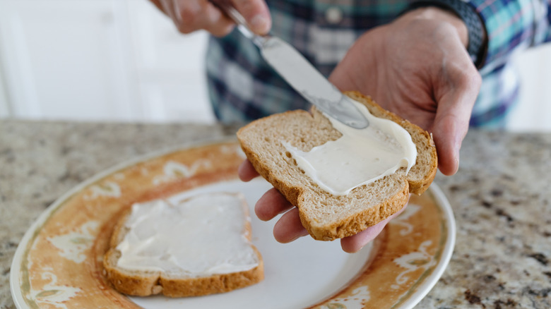 person spreading mayo on bread
