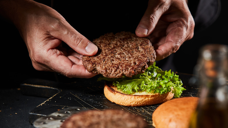 chef placing burger patty on bun