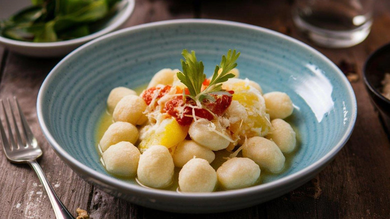A blue bowl filled with gnocchi, topped with tomato sauce.