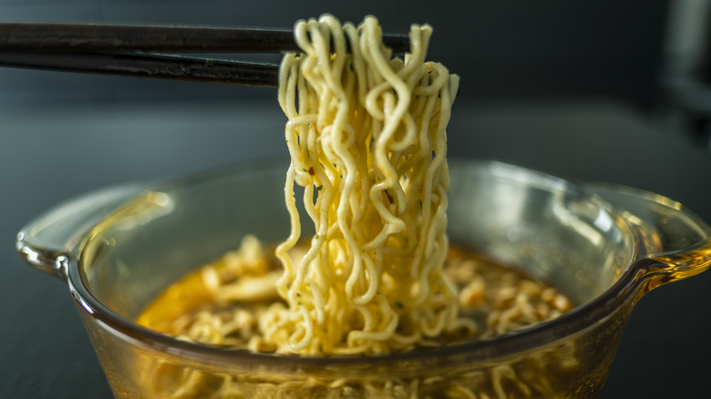 Instant ramen noodles being picked up with chopsticks