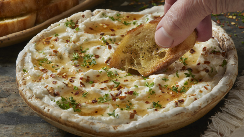 An individual dipping a piece of garlic bread into a sauce