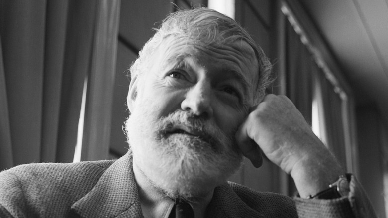 writer Ernest Hemingway resting his head against his fist