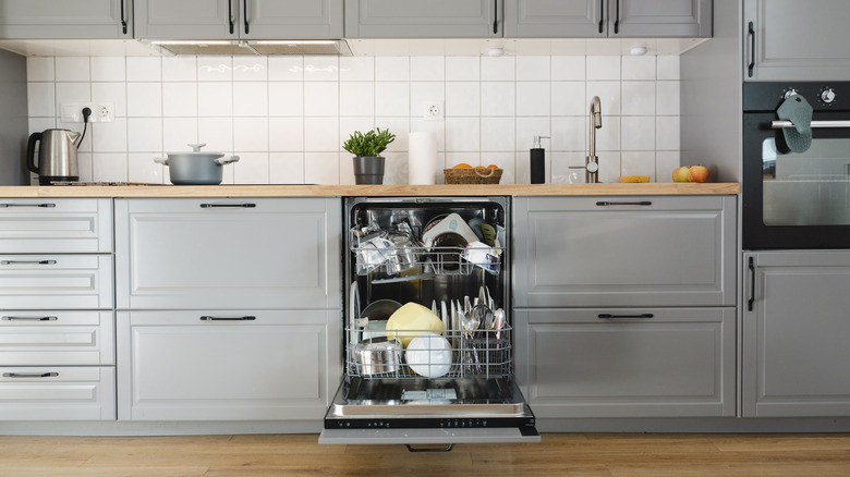 open dishwasher between gray cabinets