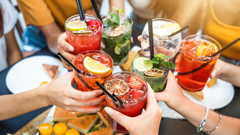 a group of friends cheers their drinks during happy hour