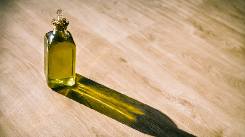 A bottle of olive oil on a wooden surface.