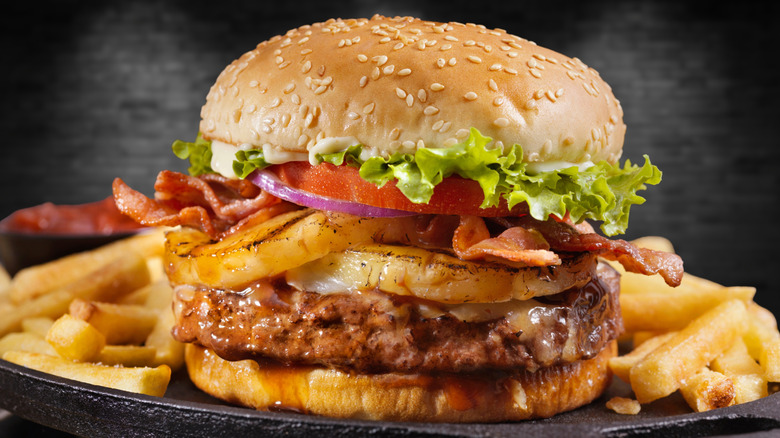 Hawaiian burger with pineapple and bacon on a plate with fries