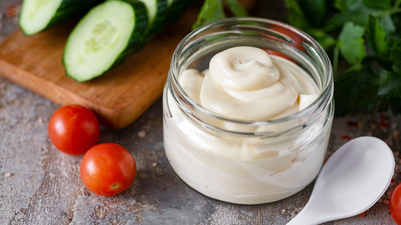 A jar of mayo surrounded by sliced vegetables.