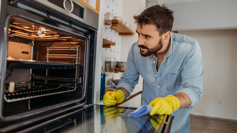 Person cleaning oven in yellow gloves