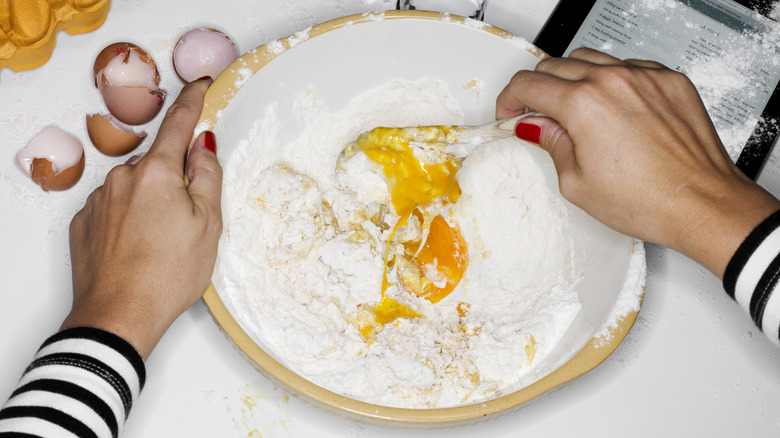 Woman wearing a striped shirt mixes eggs and flour in a bowl