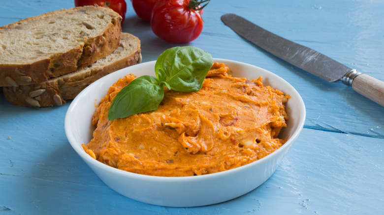 A bowl of herbed tomato butter with bread, tomatoes, and fresh basil