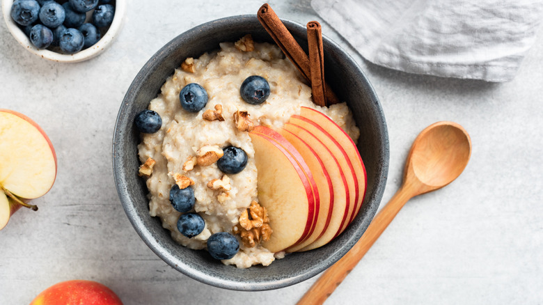 Oatmeal with blueberries, nuts, cinnamon, and apples sits on a quartz countertop.