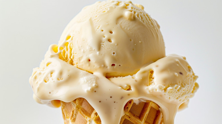 A scoop of what could be miso ice cream melting and dripping down a sugar waffle cone