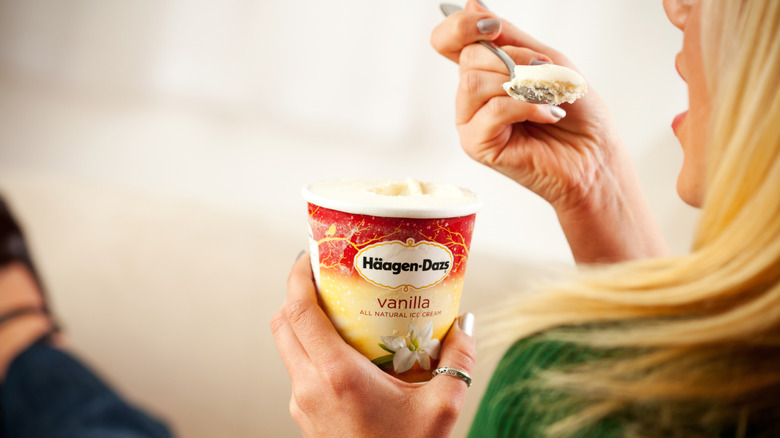 Person eating pint of vanilla ice cream