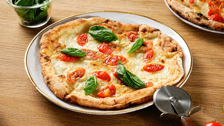 Neapolitan style pizza topped with basil and tomatoes on a plate