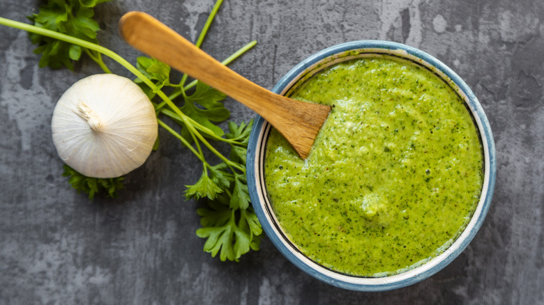 Chimichurri sauce on a grey background with fresh parsley and garlic