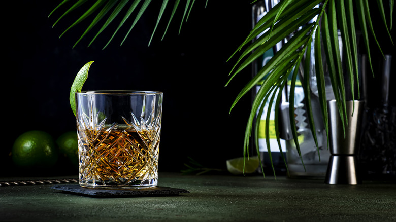 Sazerac on a dark surface beside bar equipment