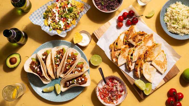 A spread featuring Mexican dishes, bottles of beer, and ingredients that are common in Mexican cuisine.