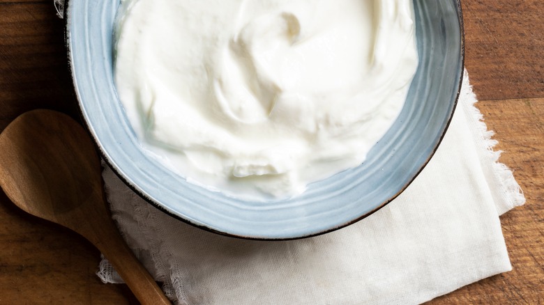 Greek yogurt in bowl on muslin with spoon