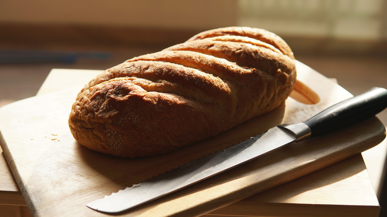 Serrated knife cutting through crusty bread