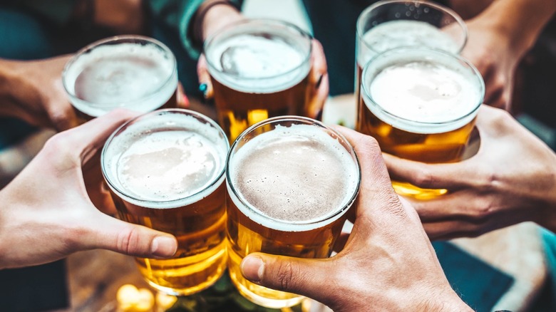 A group of friends toasting with pints of beer during happy hour.