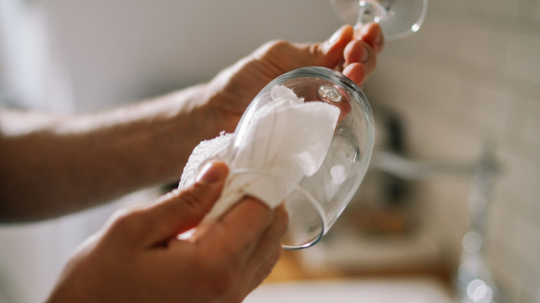 Person wiping wine glass with cloth