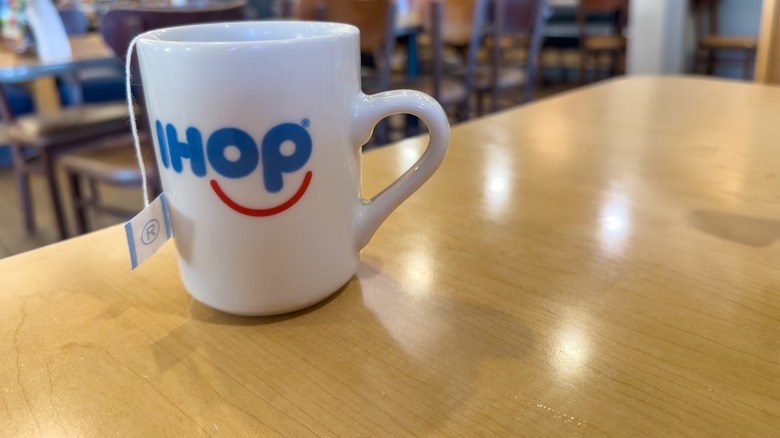 Bagged tea in a white IHOP mug on a light woodgrain table