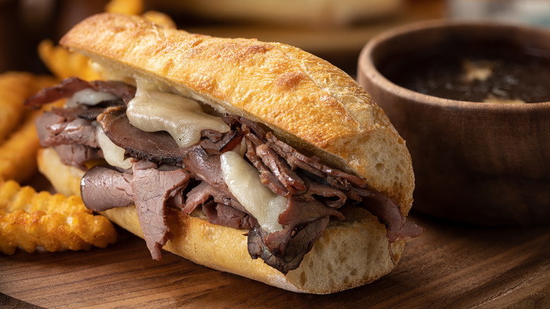 a French dip sandwich with a side of crinkle-cut fries and au jus