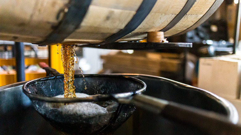 Barrel of whiskey pouring out into a strainer