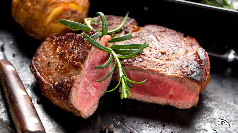 Rare steak in a cast iron pan topped with fresh rosemary
