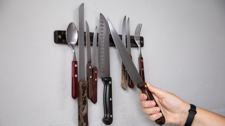 Hand placing knife of magnetic knife strip