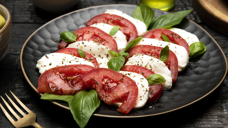 Caprese salad served on black plate