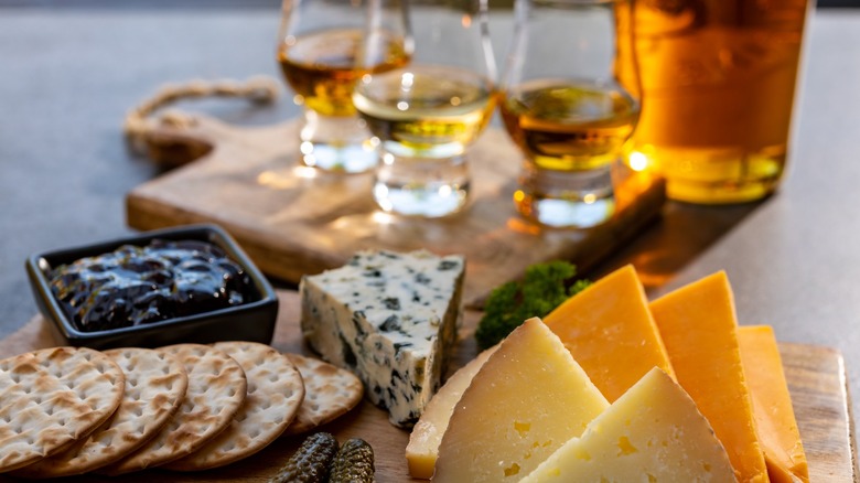 A cheese board with several glasses of whiskey