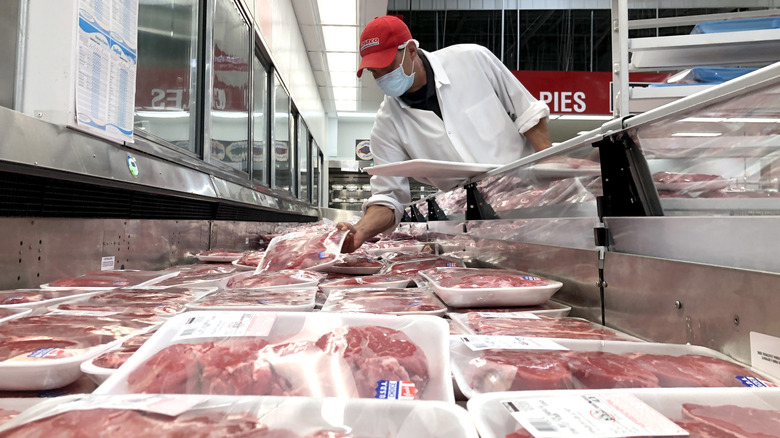 Costco butcher counter with employee stocking steak