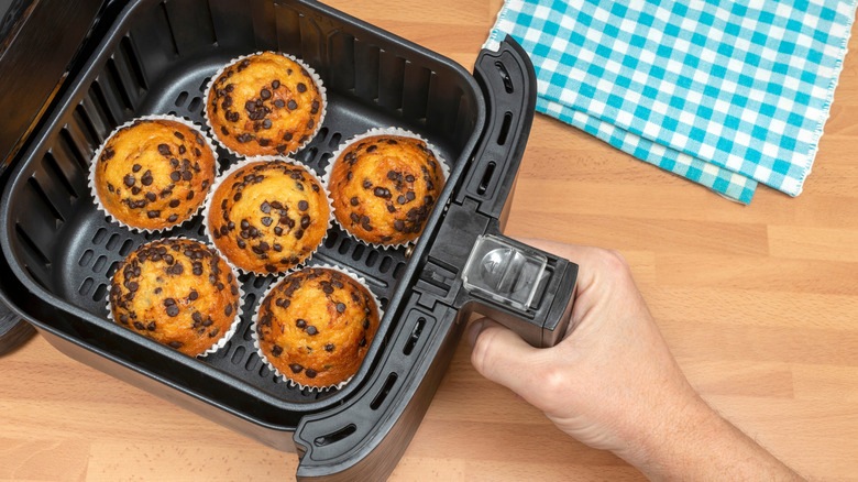 hand putting chocolate chip muffins in airfryer basket